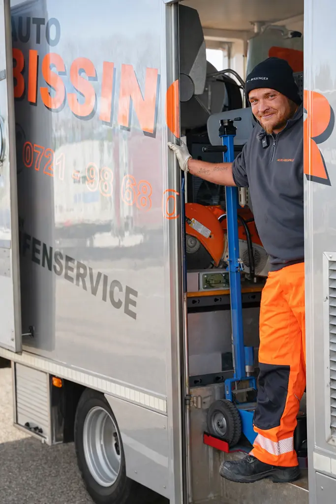 Lächelnder Mitarbeiter von Auto-Bissinger in der Tür des Servicefahrzeugs